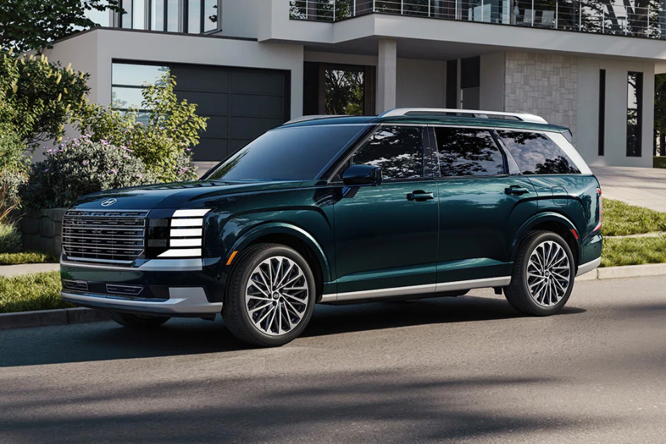 Green Hyundai Palisade SUV parked curbside in front of a modern home, shown in a front three-quarter view