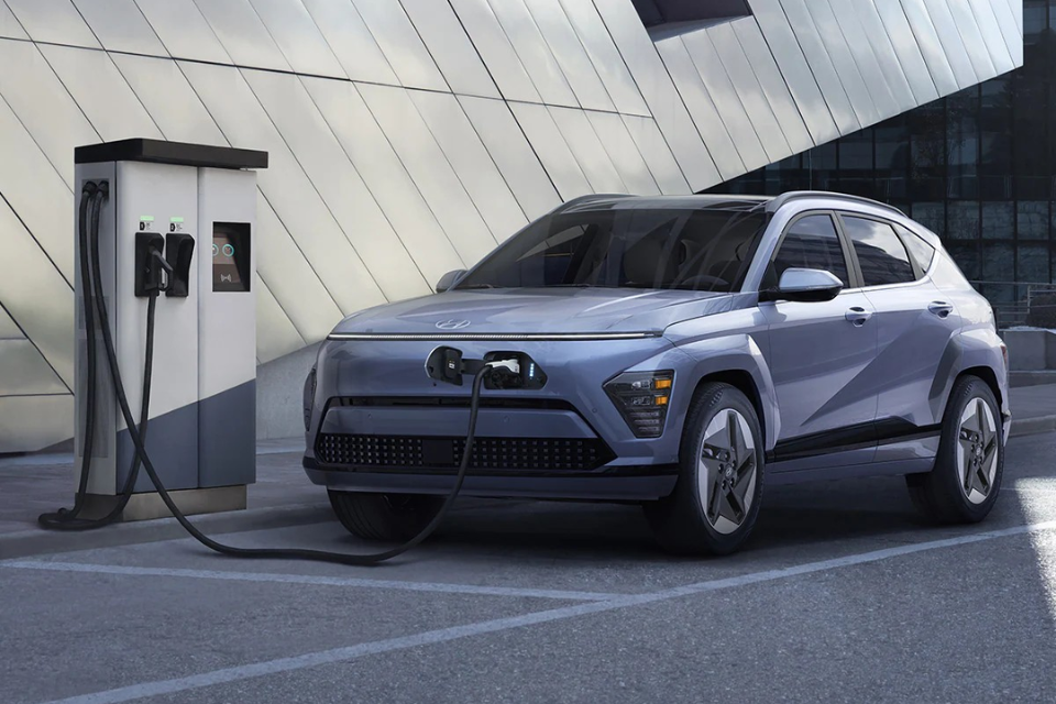 Hyundai Kona Electric parked at a public charging station with the charging cable connected to the front port.