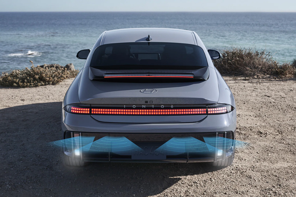 Rear view of the 2025 Hyundai IONIQ 6 driving by the ocean with pixel-style LED taillights illuminated