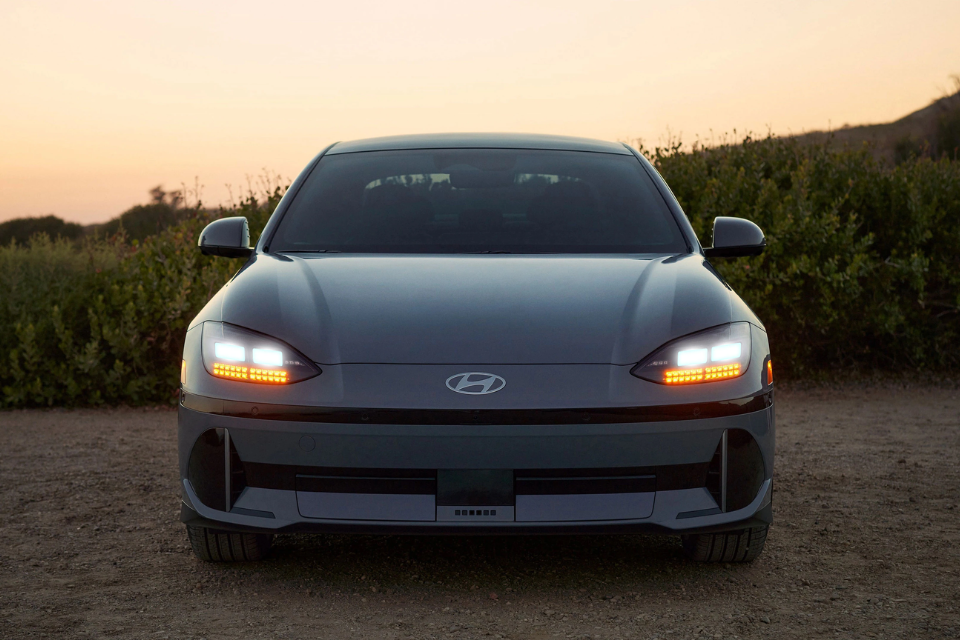 Front view of the 2025 Hyundai IONIQ 6 at dusk with LED headlights and turn signals illuminated