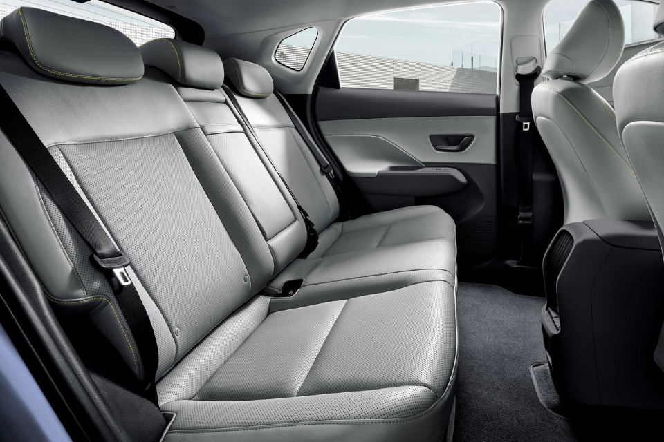 Hyundai Kona Electric rear-seat interior shown in light upholstery with contoured seating and generous legroom.