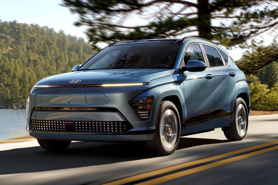 Hyundai Kona Electric in motion on a scenic road, showcasing its sleek front design and LED lighting.