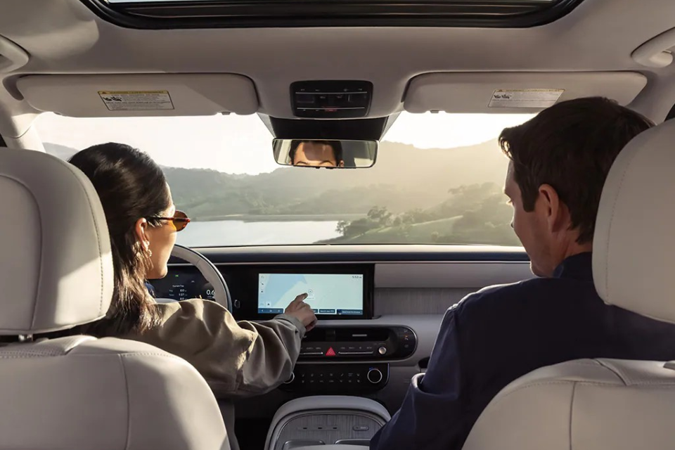 Interior lifestyle shot of passengers enjoying the cabin comfort and panoramic-style open feel inside the Palisade Hybrid.