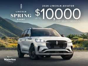 A white 2026 Lincoln Aviator SUV is parked on a scenic mountain road at sunset with rolling hills in the background. Overlaid text reads “Lincoln Spring Event – 2026 Lincoln Aviator – Up to $10,000 off select models – Waterloo Lincoln.”