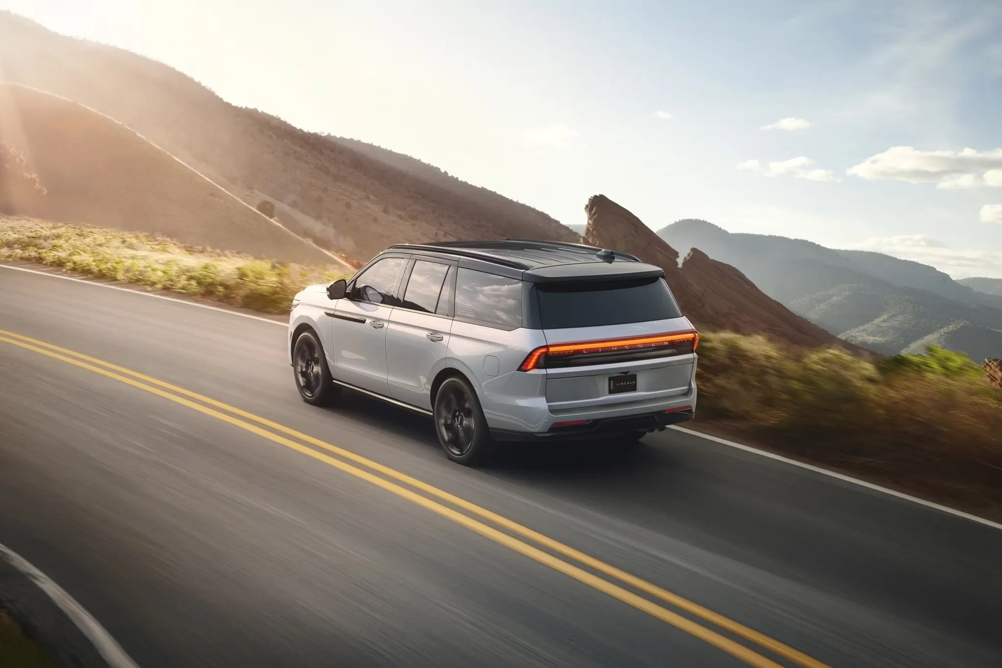 2026 Lincoln Navigator luxury SUV driving on open road rear three quarter view