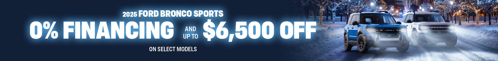 A blue Bronco Sport and a white Bronco Sport drive along a snowy, tree lined street with twinkling winter lights and a skyscraper skyline in the background. The graphic features zero percent financing OAC and up to sixty five hundred dollars off select models.