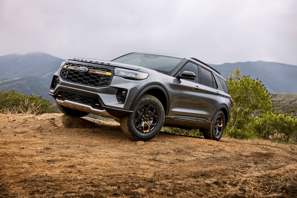 A gray 2026 Ford Explorer Tremor from Freedom Ford tackling an off-road trail, showcasing its rugged design and bold stance against a mountain backdrop.