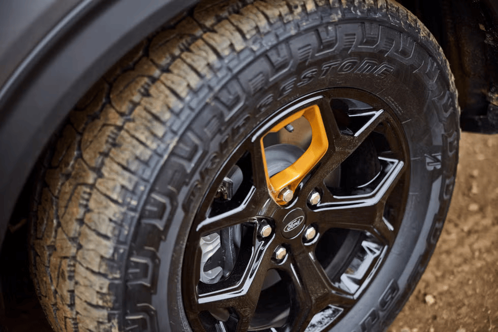 Close-up of the 2026 Ford Explorer Tremor wheel and tire from Freedom Ford, featuring black alloy rims with yellow accents and rugged Firestone all-terrain tires.