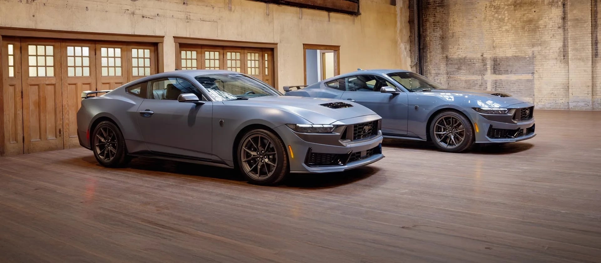Two 2026 Ford Mustangs side by side in Vapour Blue, showcasing aggressive exterior styling, sleek body lines, and performance-focused design.