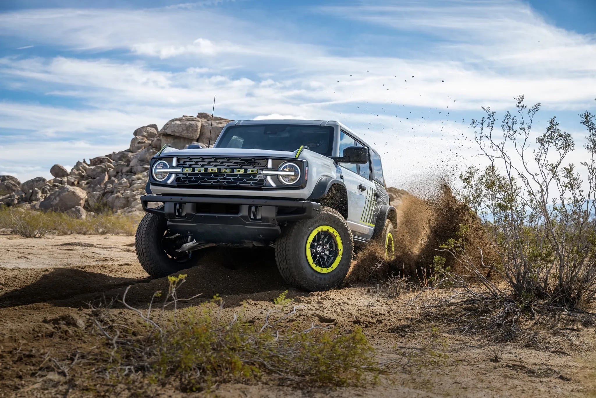 Ford Bronco RTR edition navigating rugged off-road terrain, kicking up dirt and rocks, showcasing its enhanced suspension, aggressive tires, and off-road performance capabilities.