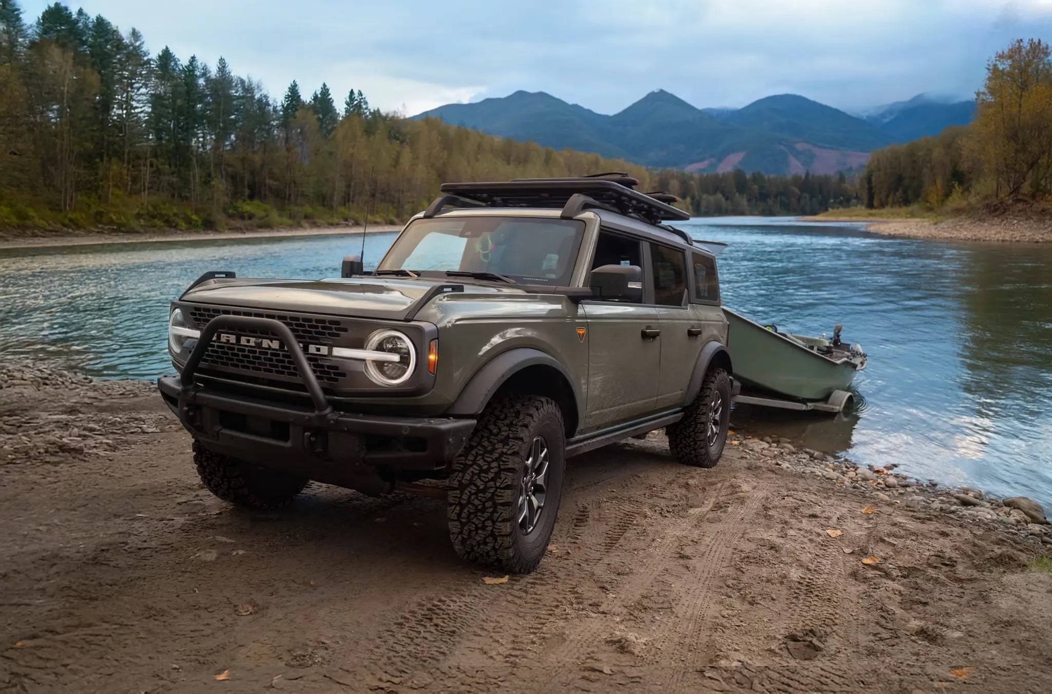 2026 Ford Bronco towing and launching a boat at a mountain lake, set against the scenic Rocky Mountains backdrop.
