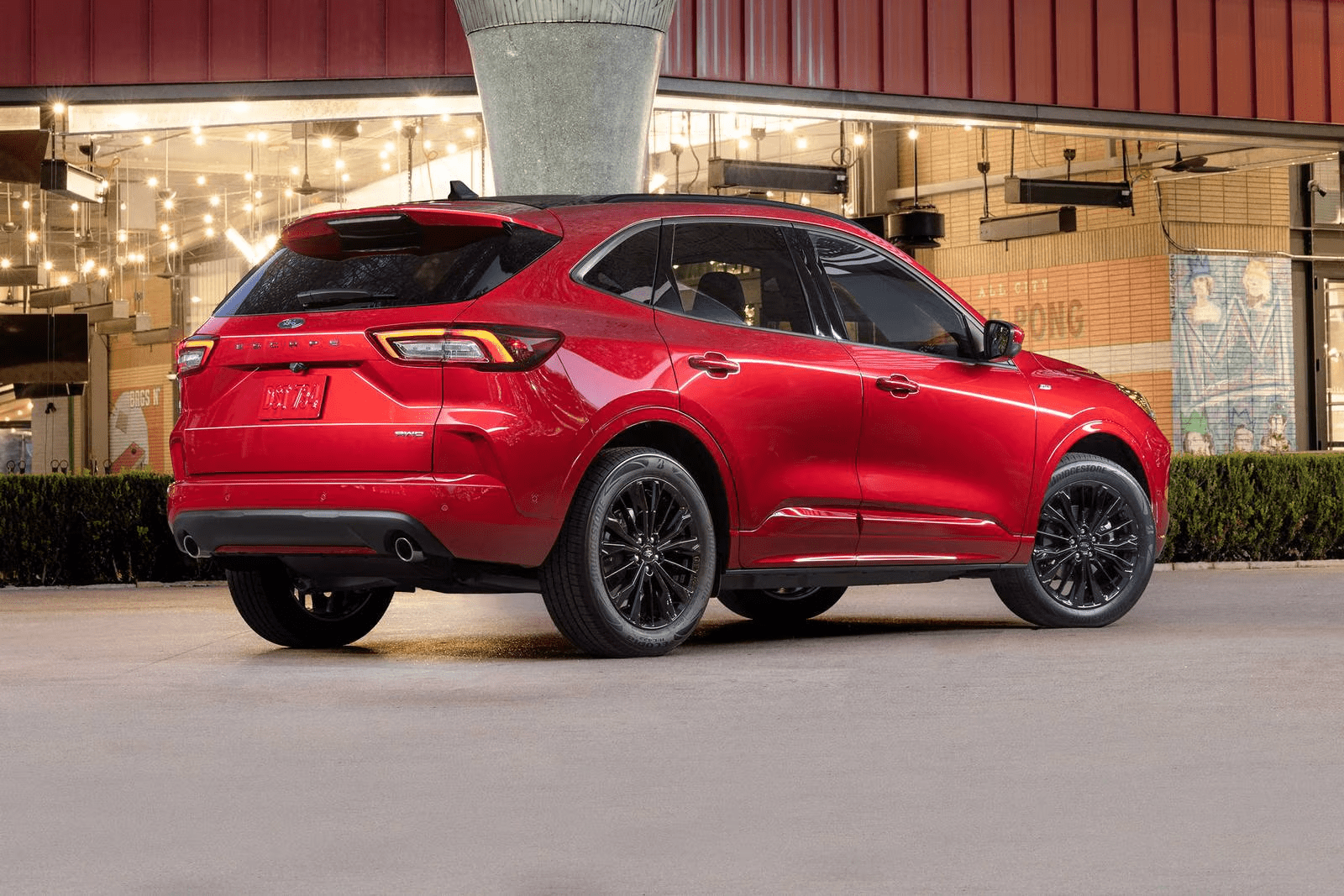 Red Ford Escape SUV viewed from the rear under evening lights.
