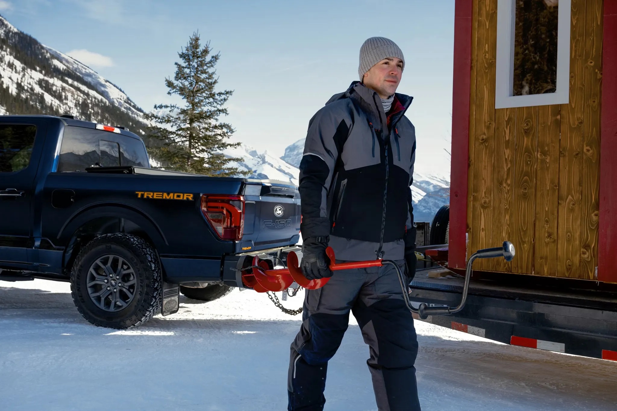 Person standing beside a 2026 Ford F-150 near a cabin