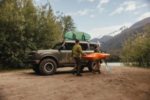 Ford Bronco parked at a campsite with tents and outdoor gear, highlighting its versatility and adventure-ready capability.
