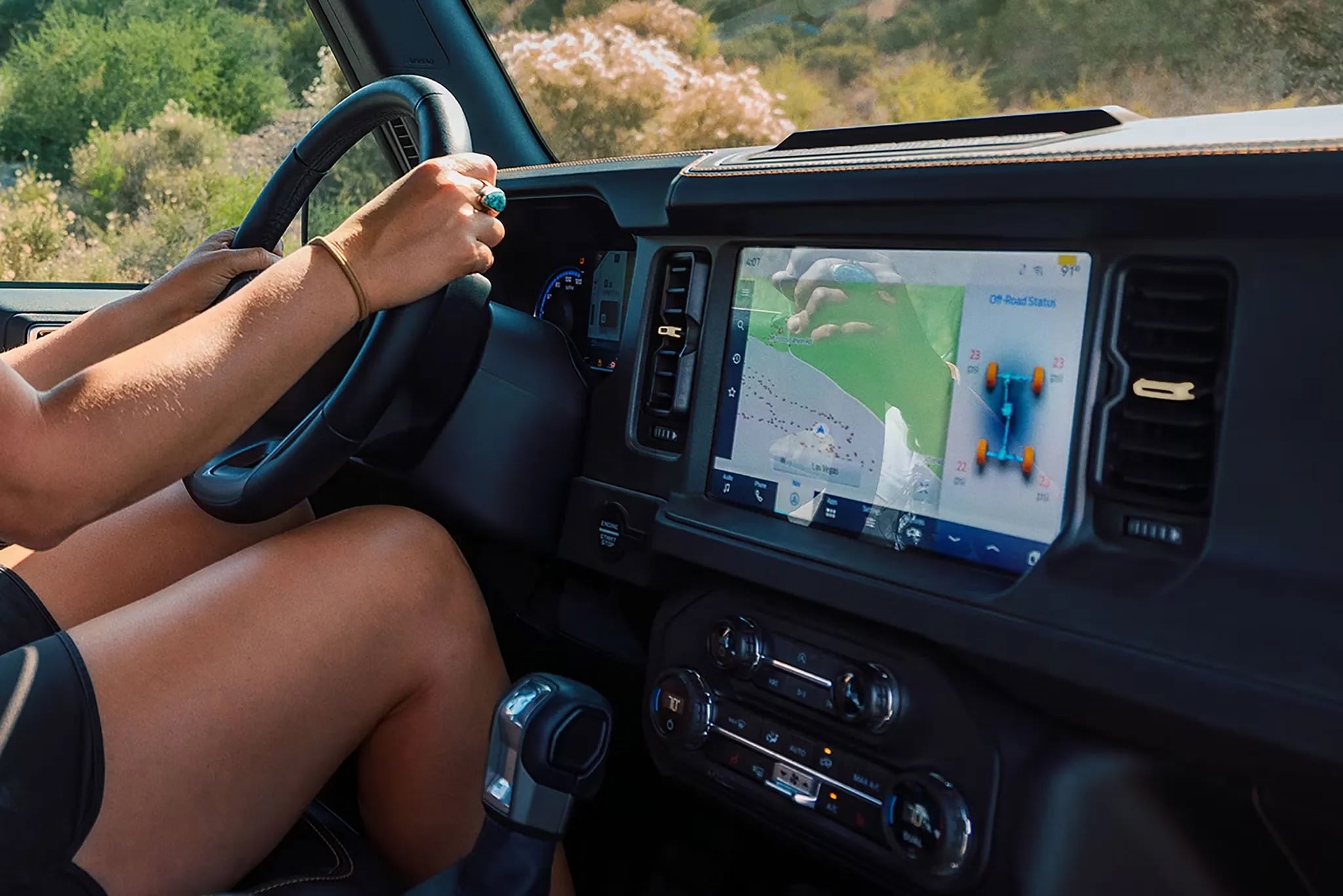 Ford Bronco interior focusing on the center touchscreen displaying the SYNC® 4 infotainment system, showing navigation, media, and connectivity features.