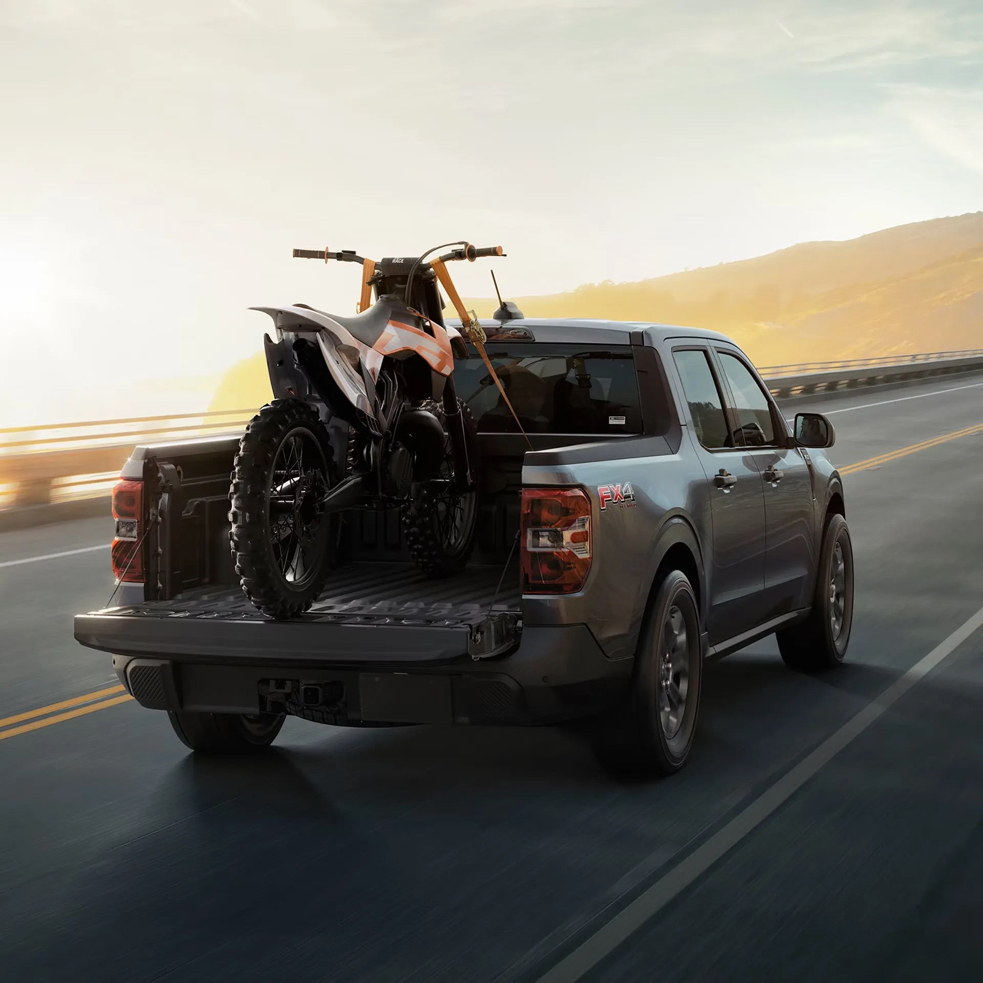 2026 Ford Maverick hauling ATV in truck bed rear driving view