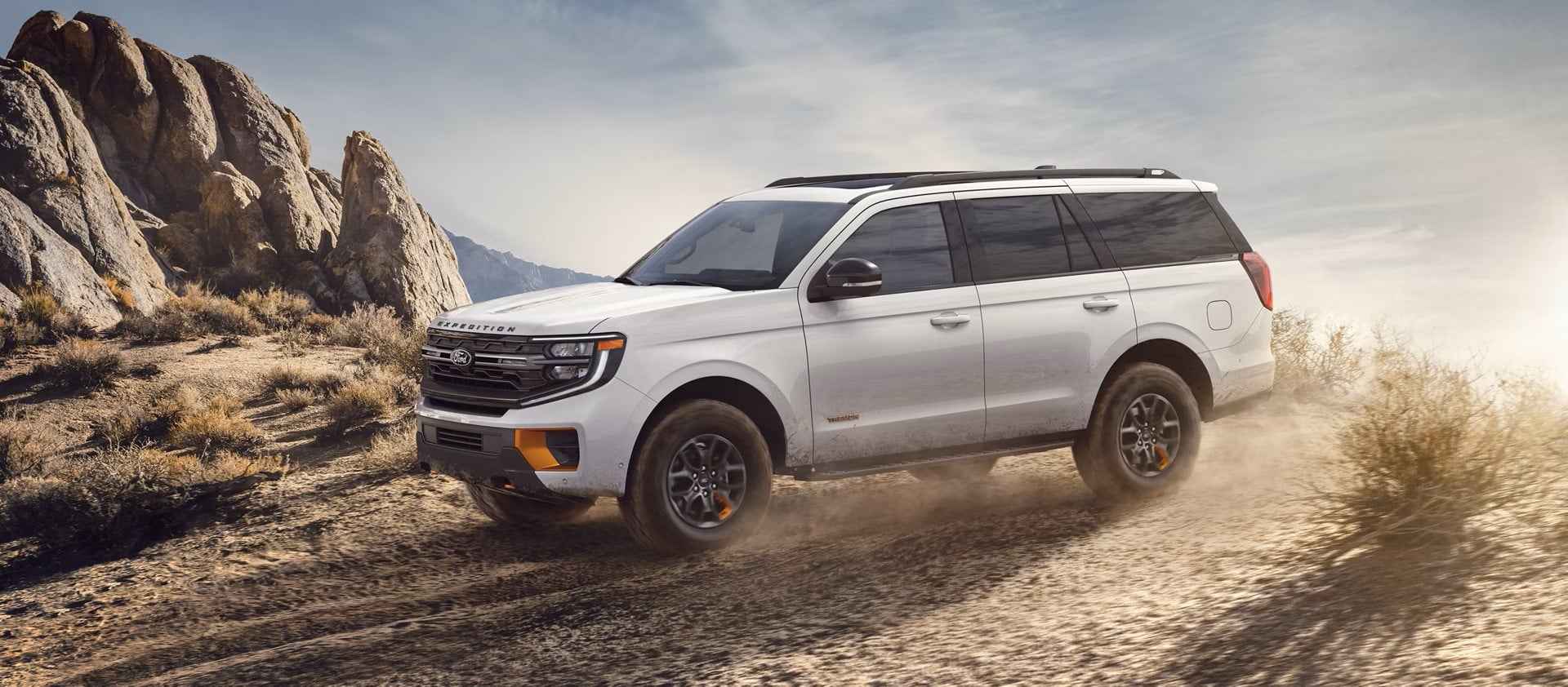 Ford Expedition driving on a dirt trail, kicking up dust.