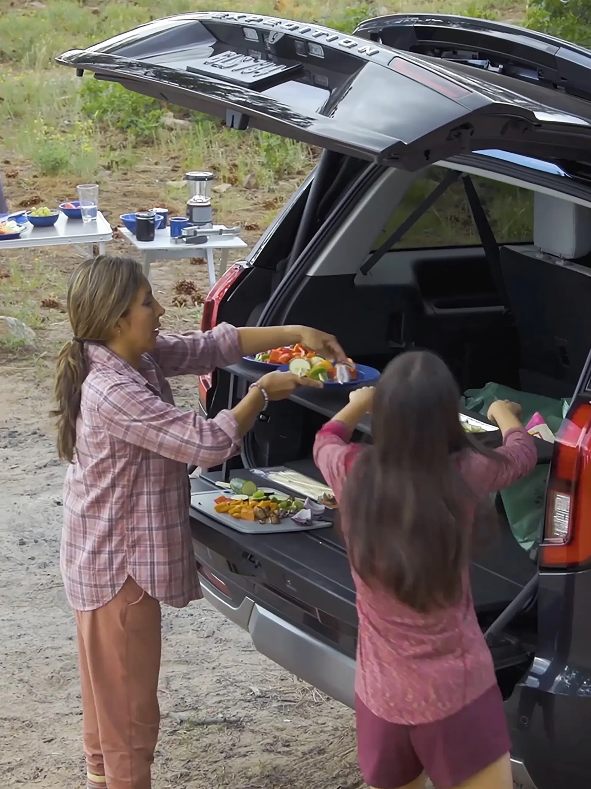 Family loading gear into the rear cargo area of a Ford Expedition.
