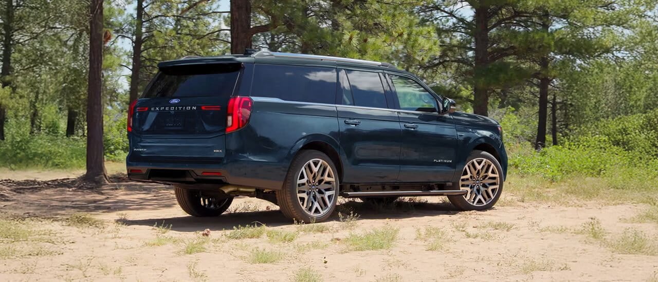 Black 2027 Ford Expedition driving on a wooded road