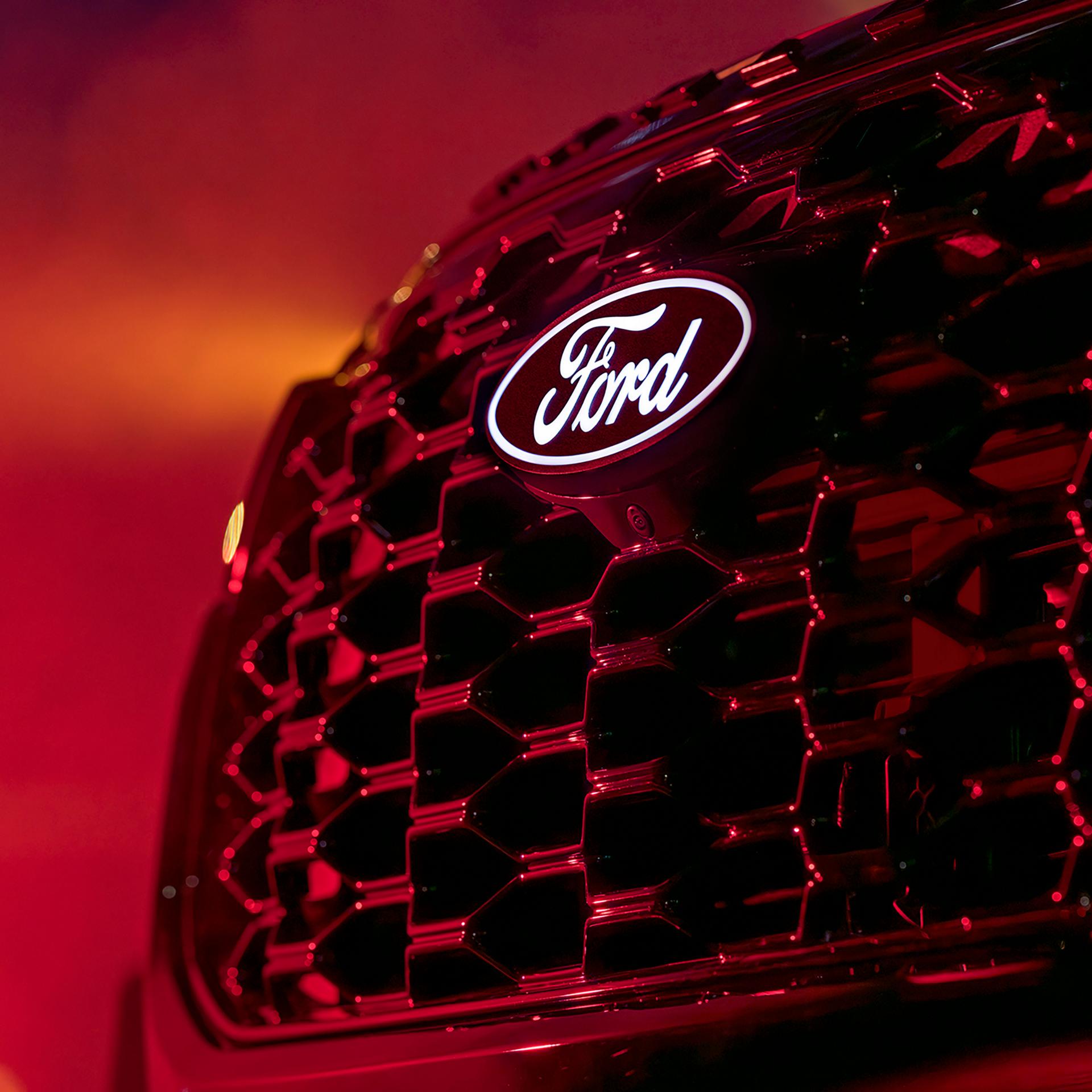 Close-up of the Ford badge and Explorer front grille under red lighting