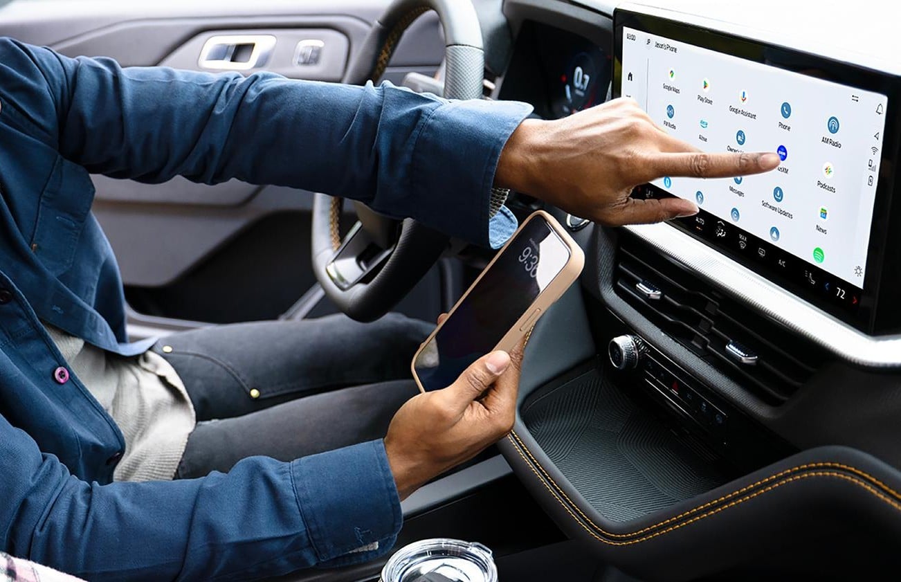 Driver pointing to the centre touchscreen inside a 2027 Ford Explorer