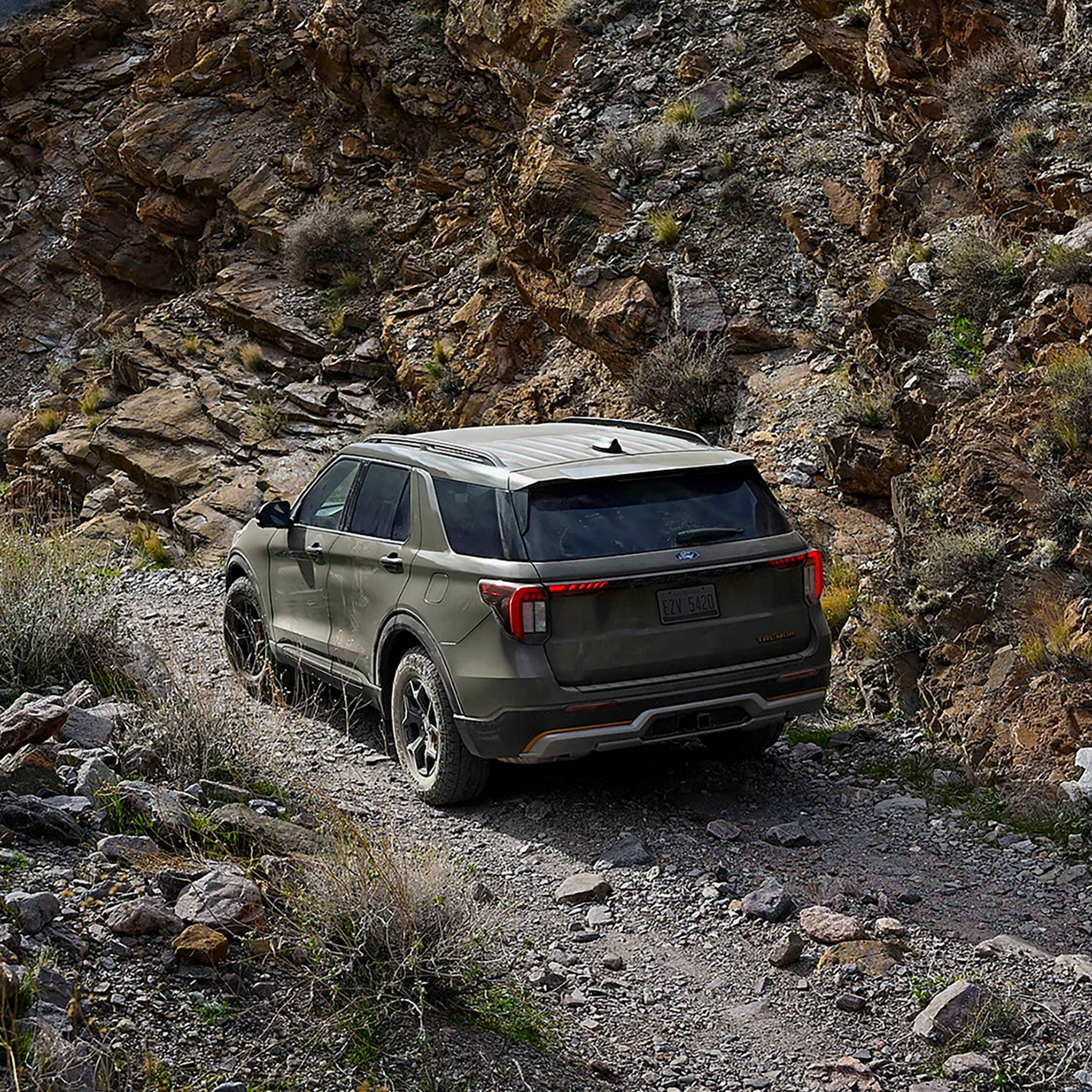 Rear view of a 2027 Ford Explorer travelling along a rocky mountain trail