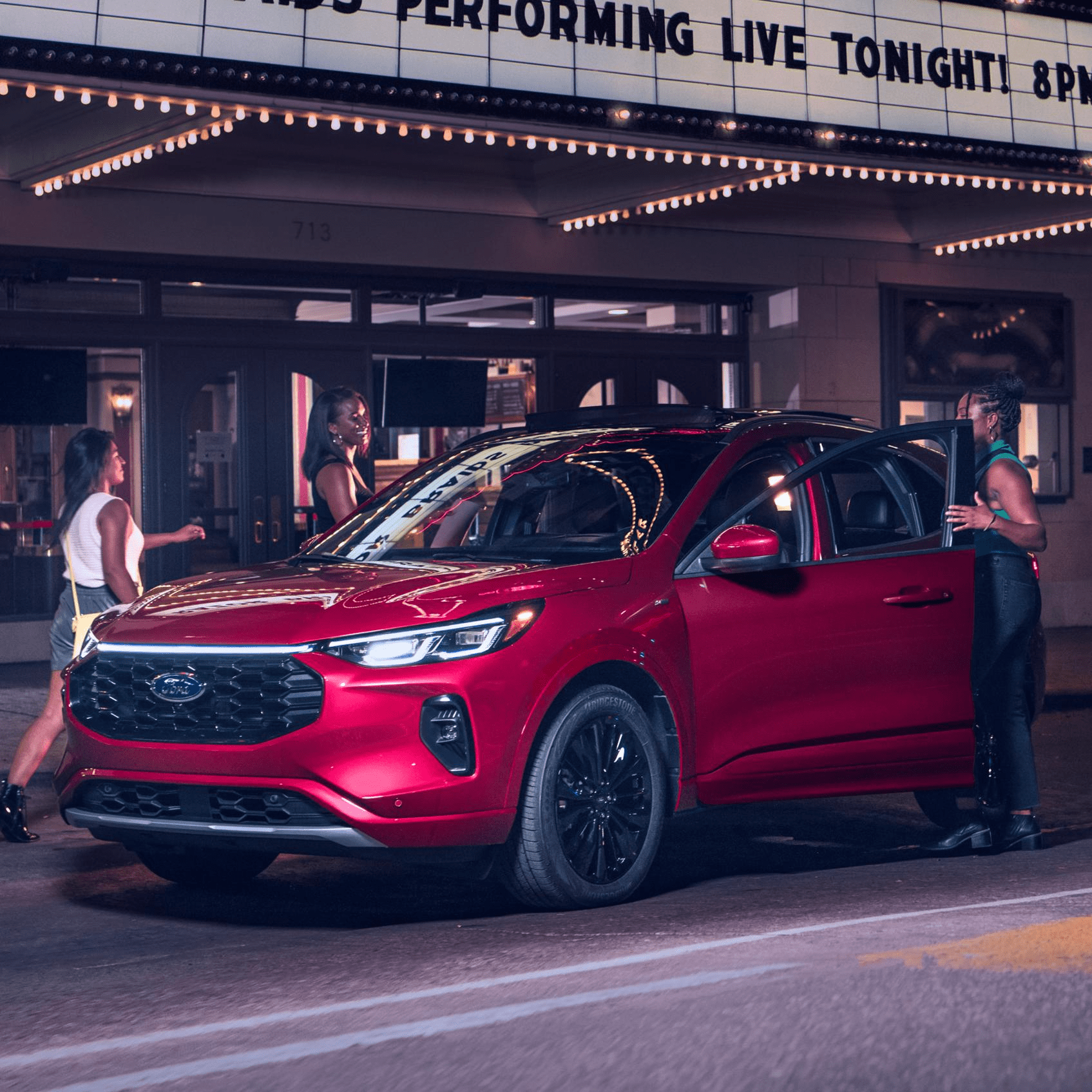 A red Ford Escape parked under bright city lights, ready for a night out.