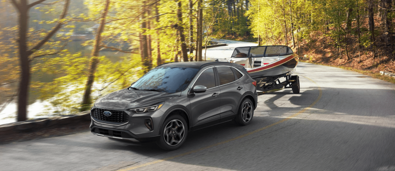 2026 Ford Escape driving and towing something with trees in background