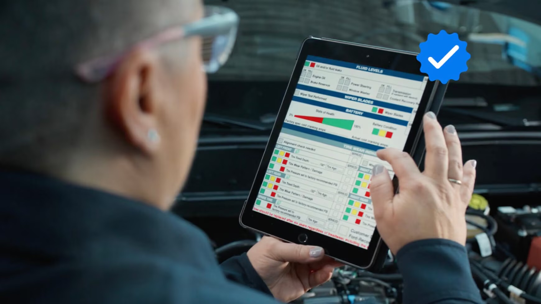 Mid-Town Ford technician using digital battery health report to assess service needs during winter vehicle inspection in Winnipeg.