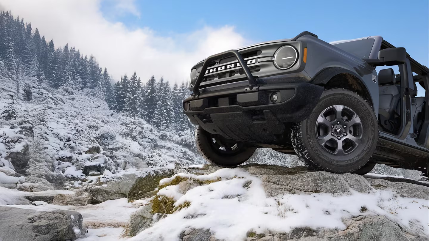 Ford Bronco Sport climbing snowy rocks in Manitoba wilderness, featured in Mid-Town Ford’s Winnipeg December year-end clearance event.