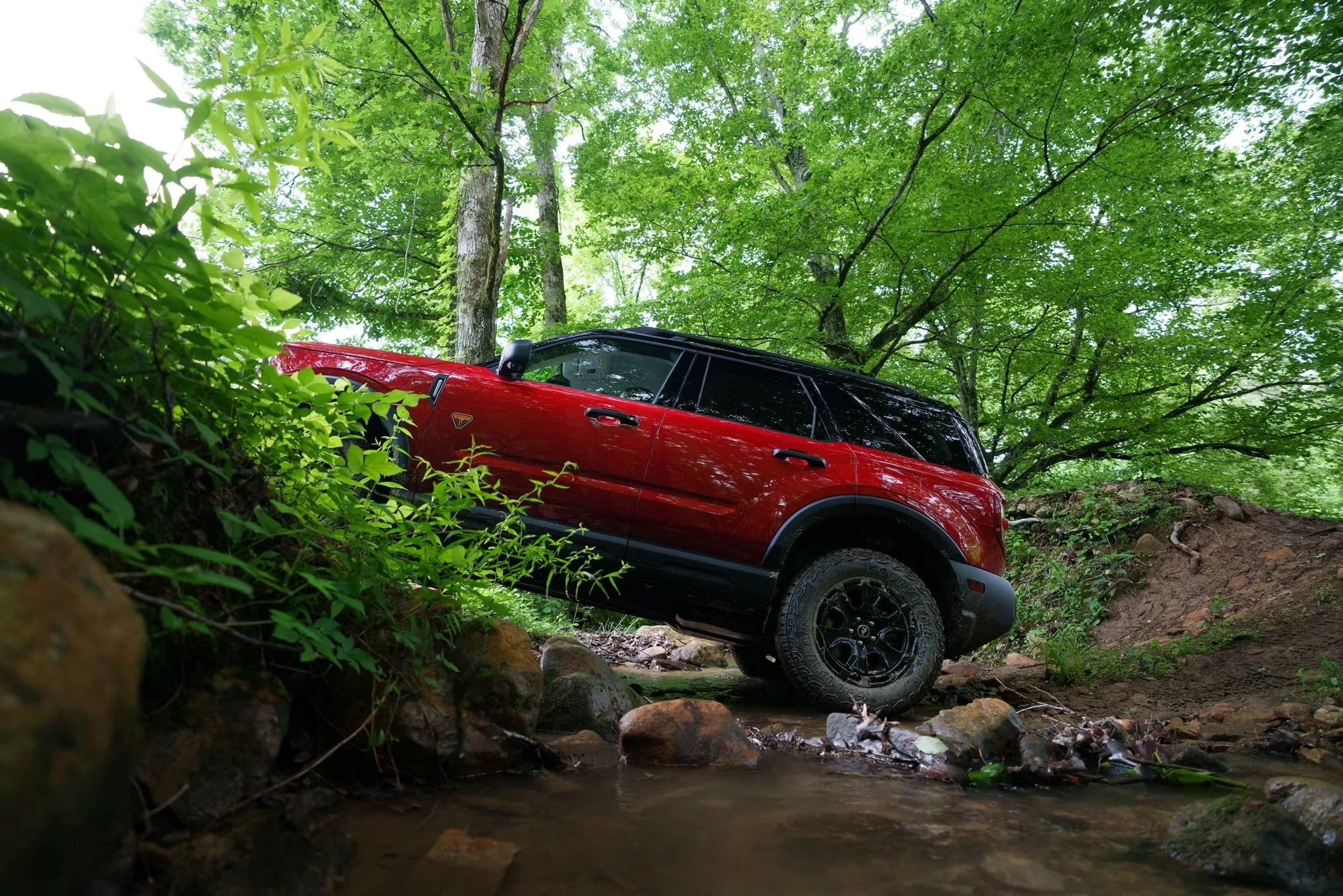 Red 2026 Ford Bronco Sport driving through a forested area