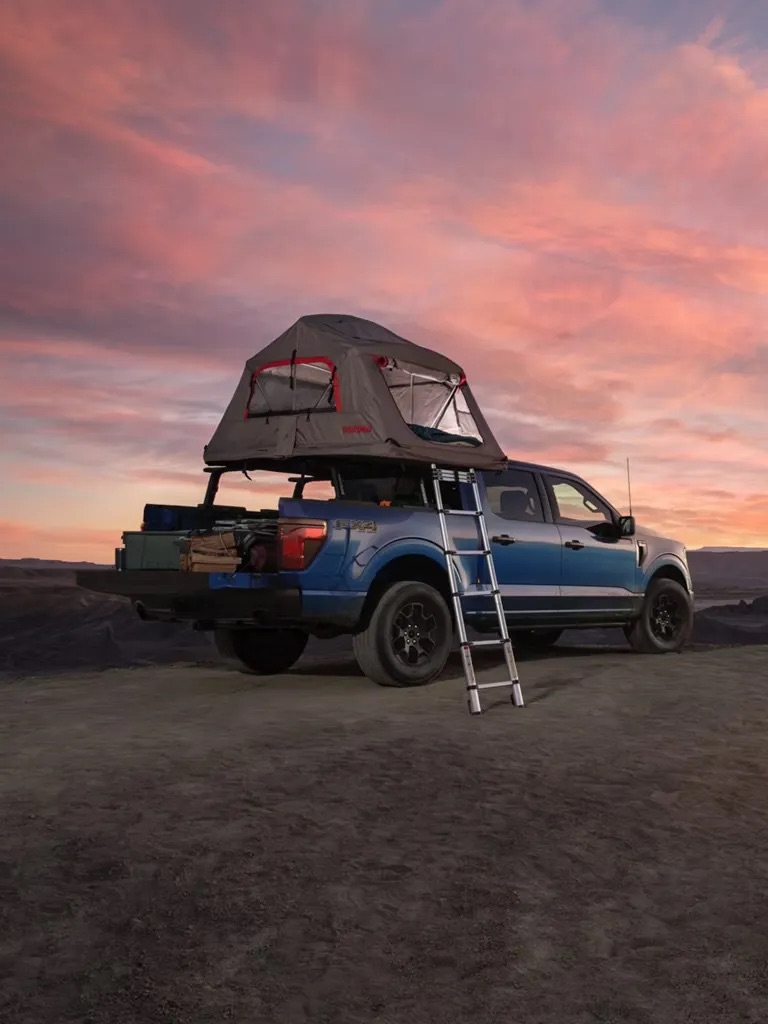 Pickup truck with rooftop tent set up at sunset