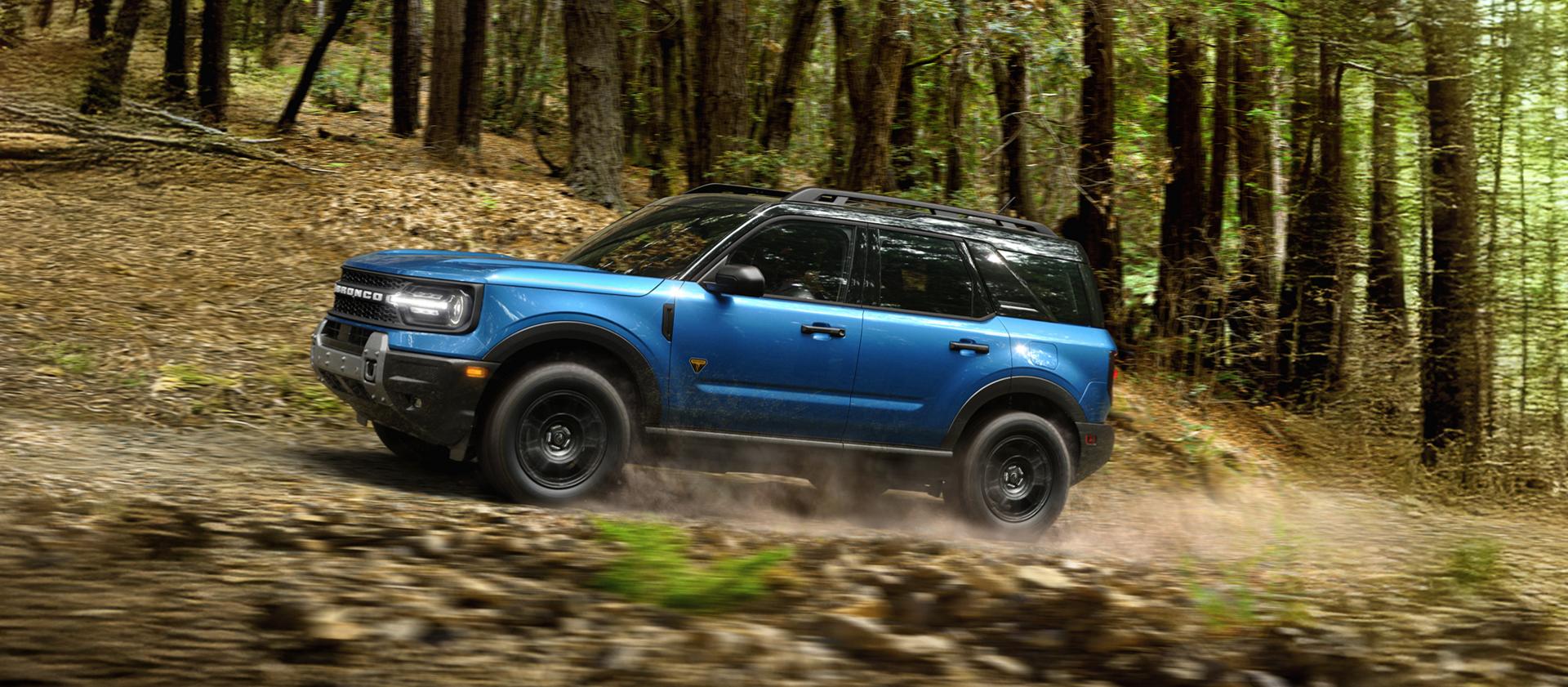 Blue 2026 Ford Bronco Sport driving through a forest trail
