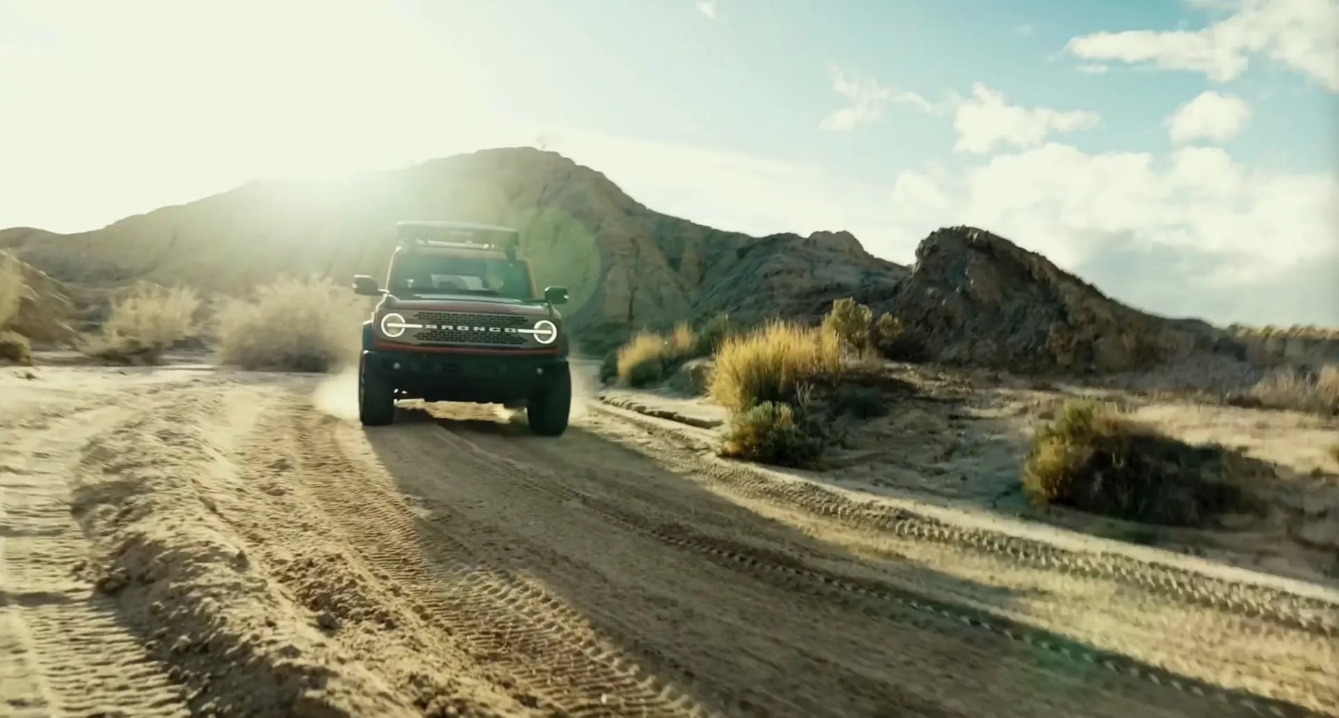 2026 Ford Bronco driving through dusty trail off road action shot