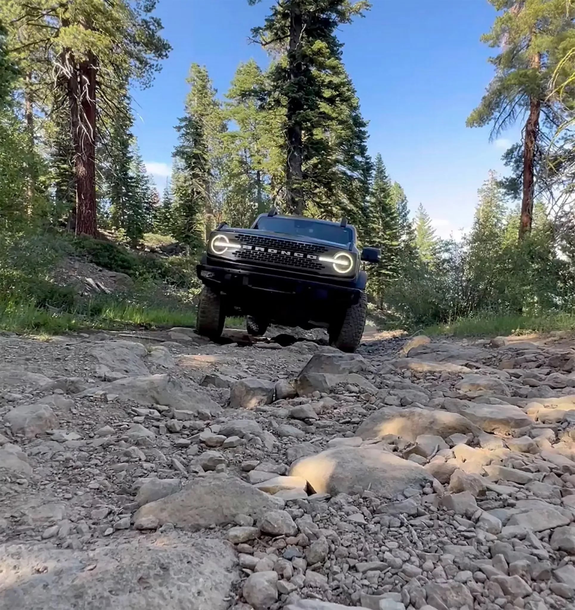 2026 Ford Bronco off road driving through rocky forest trail terrain