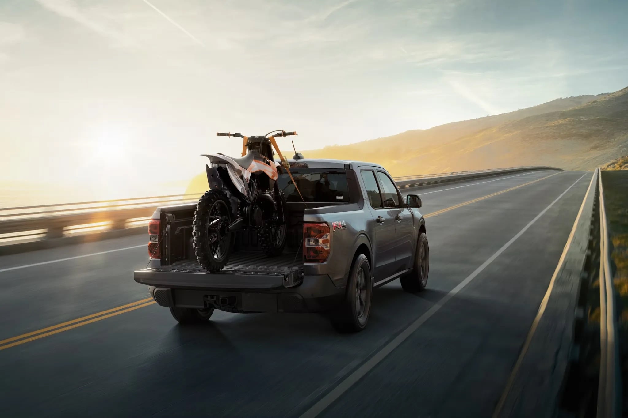 2026 Ford Maverick hauling ATV in truck bed on highway
