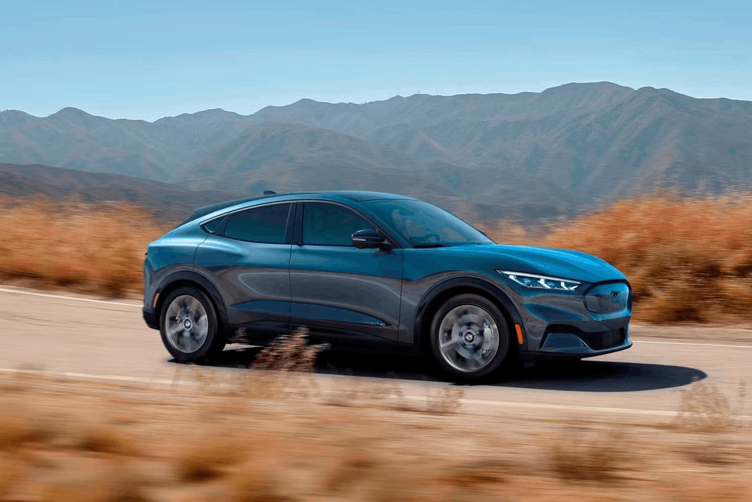 2026 Ford Mustang Mach-E blue electric SUV driving on open road side view
