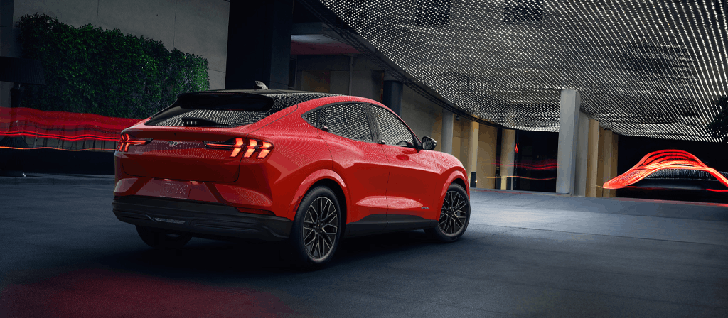2026 Ford Mustang Mach-E red electric SUV driving through urban setting
