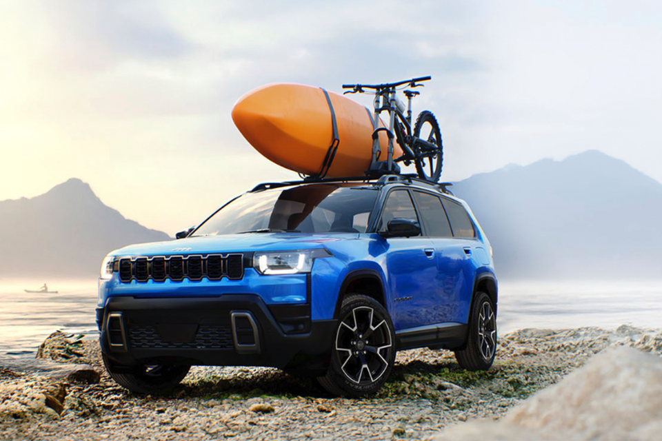 2026 Jeep Cherokee in blue parked by a lake with a kayak and bicycle mounted on the roof, ready for an outdoor adventure