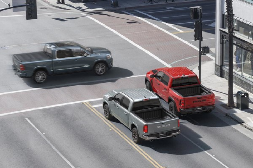 2026 Ram 1500 trucks in motion on a city intersection, showcasing bold exterior styling and modern design