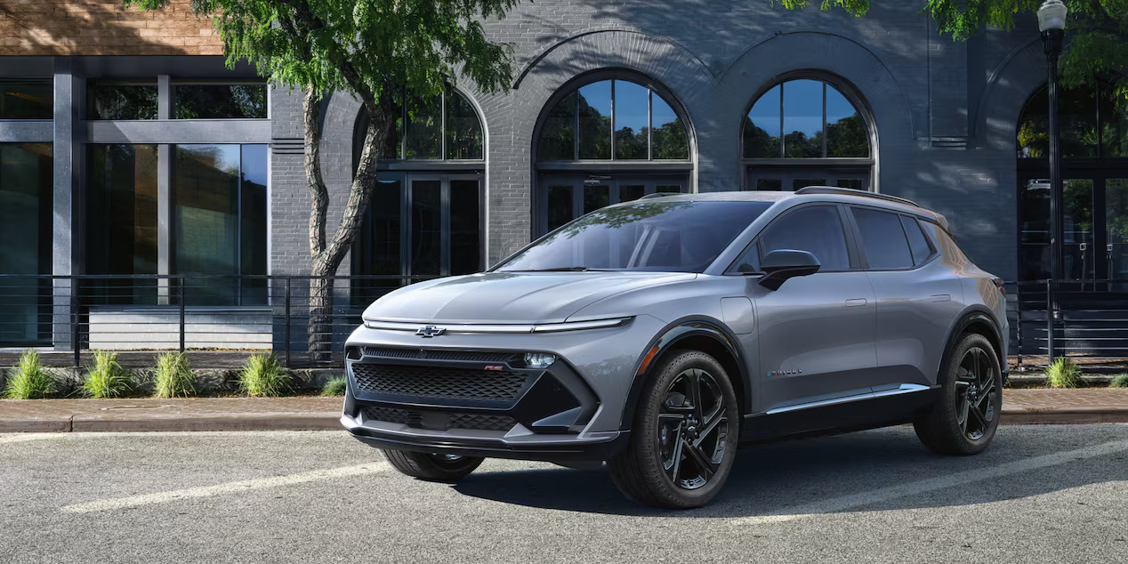 Front-side view of a 2025 Chevrolet Equinox EV parked alone in the parking lot near a building