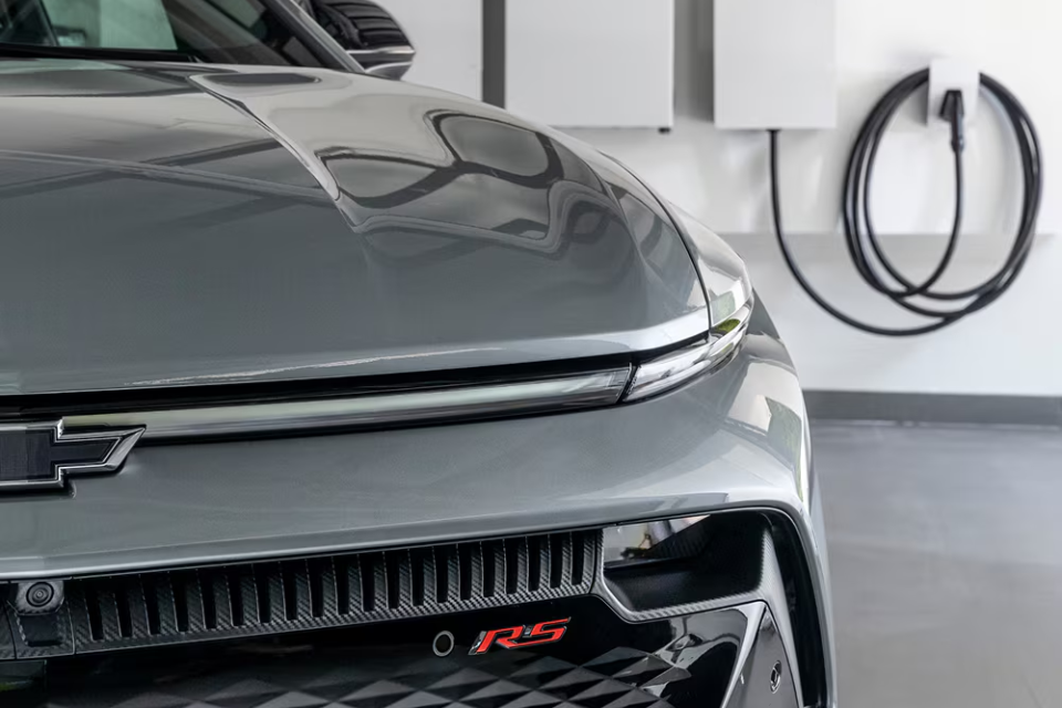 Close-up of the 2026 Chevrolet Equinox EV RS front end plugged in and charging in a home garage