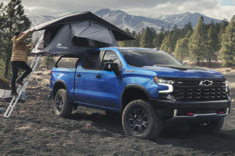 2026 Chevrolet Silverado 1500 ZR2 in blue parked at a campsite with a rooftop tent, highlighting its off-road versatility
