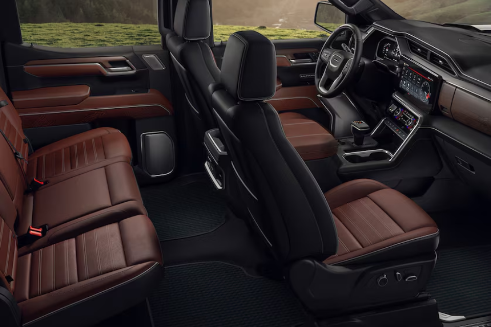 Interior view of the 2026 GMC Sierra HD featuring luxurious brown and black leather seats with wood trim accents