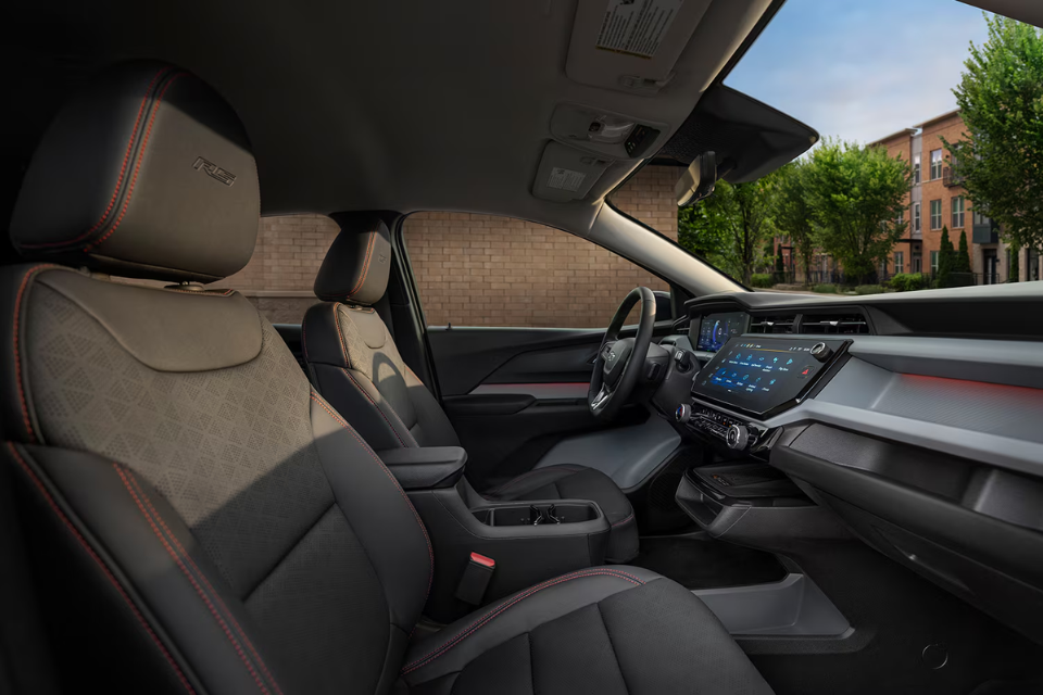 Interior of the 2027 Chevrolet Bolt EV featuring black seats with red stitching and a large touchscreen display