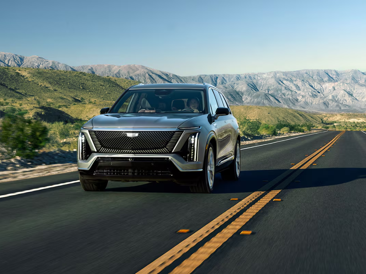 2026 Cadillac VISTIQ in motion against a mountainous desert backdrop, showcasing vertical LED headlights and bold grille design