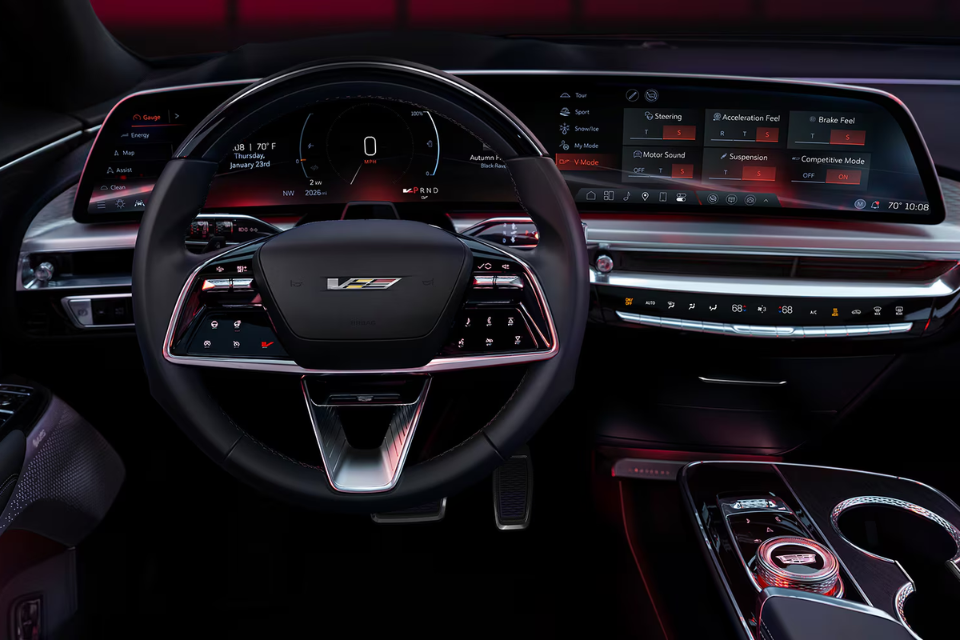Driver’s cockpit of the 2026 Cadillac Lyriq illuminated in red ambient lighting, displaying a wide curved digital display