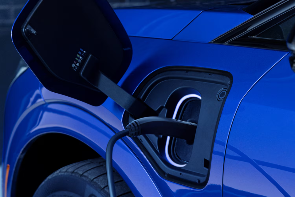 Close-up of the 2026 Cadillac Optiq charging port connected to a charger, representing its all-electric capability