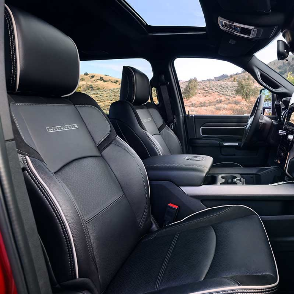 Interior of 2025 Ram 2500 HD Laramie showing premium black leather front seats with contrast stitching and panoramic sunroof