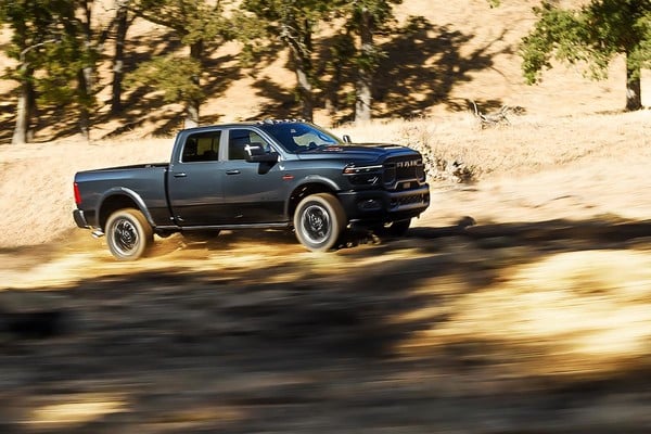 Black 2025 Ram 2500 HD Power Wagon driving off-road through a dry, grassy landscape